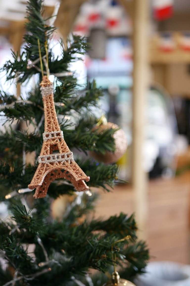 Close-up of Eiffel Tower ornament on a Christmas tree, capturing festive vibes indoors.